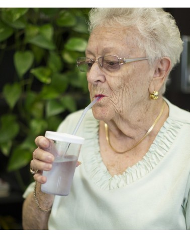 Ältere Dame trinkt aus dem Sip-Tip Trinkbecher.
